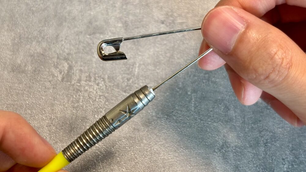 ダーツのシャフトとチップが中折れした場合の安全ピンで破片を救出している写真。